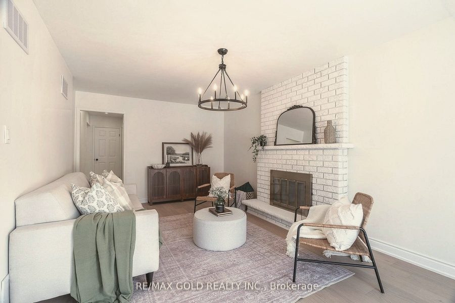 Living room with a white brick fireplace, cream sofa, sage throw and rattan lounge chair