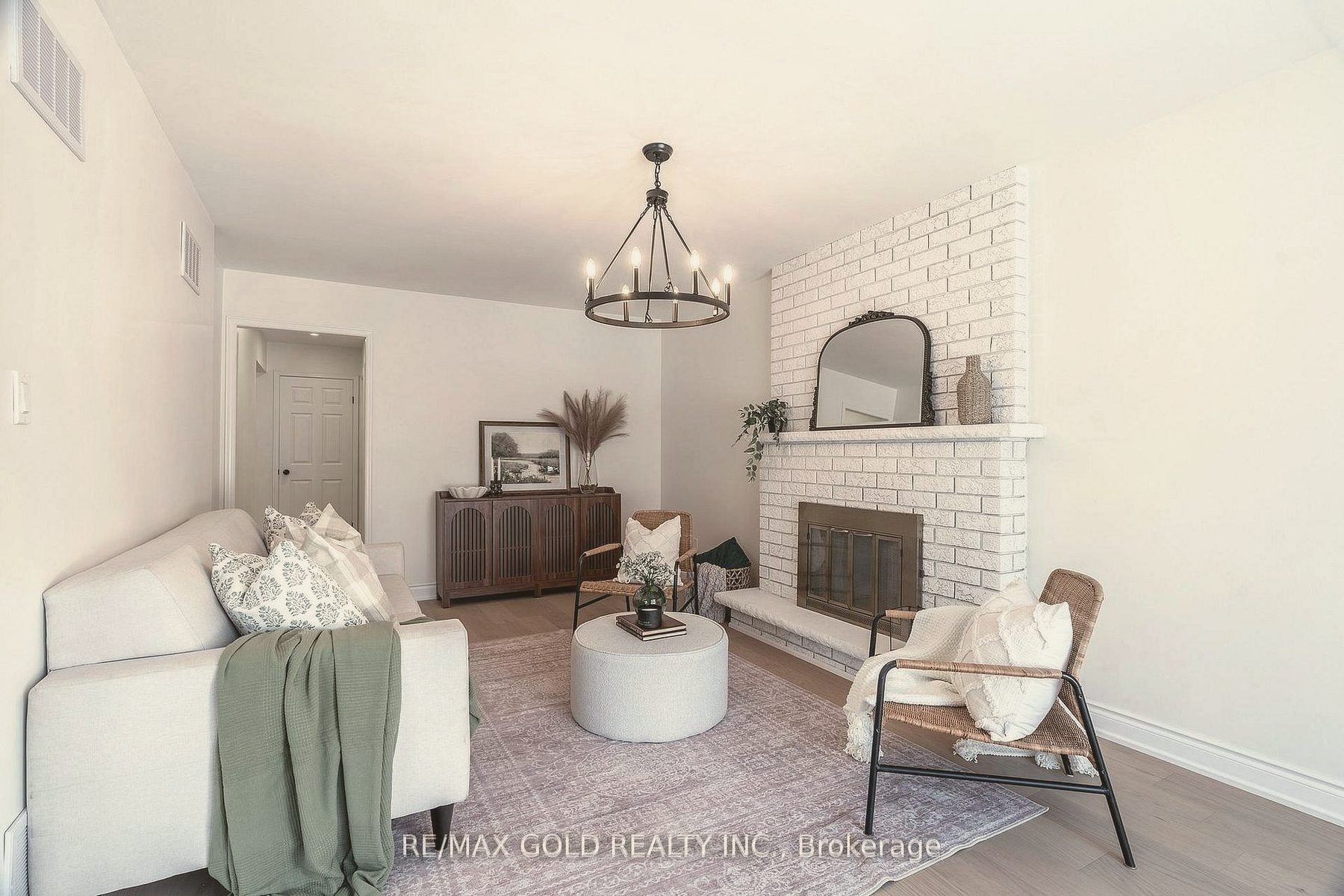 Living room with a white brick fireplace, cream sofa, sage throw and rattan lounge chair