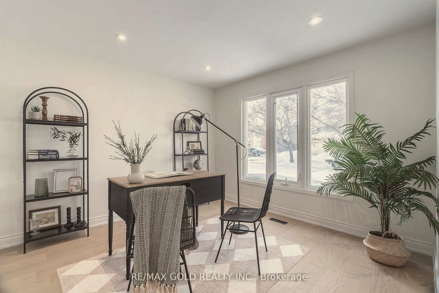 Home office with a black desk, arched shelving and a potted palm
