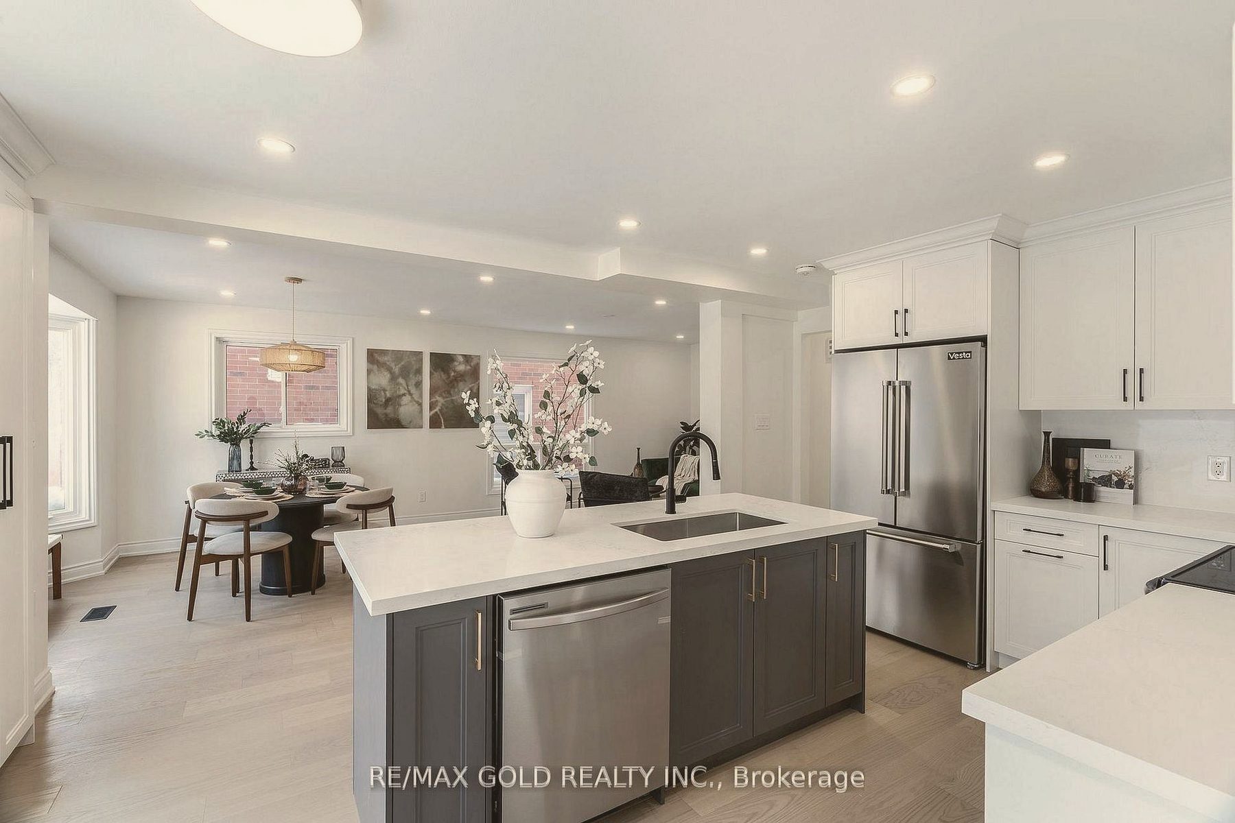 White kitchen with a charcoal island and a styled dining nook beyond