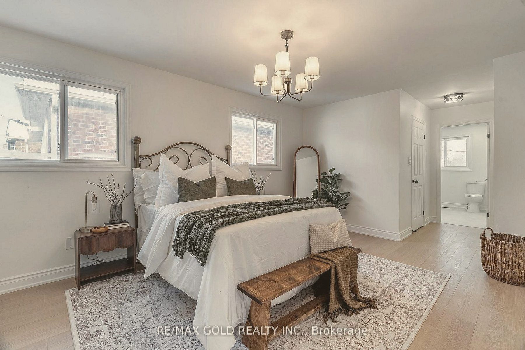 Bedroom with an iron bed, layered white linens and an olive throw