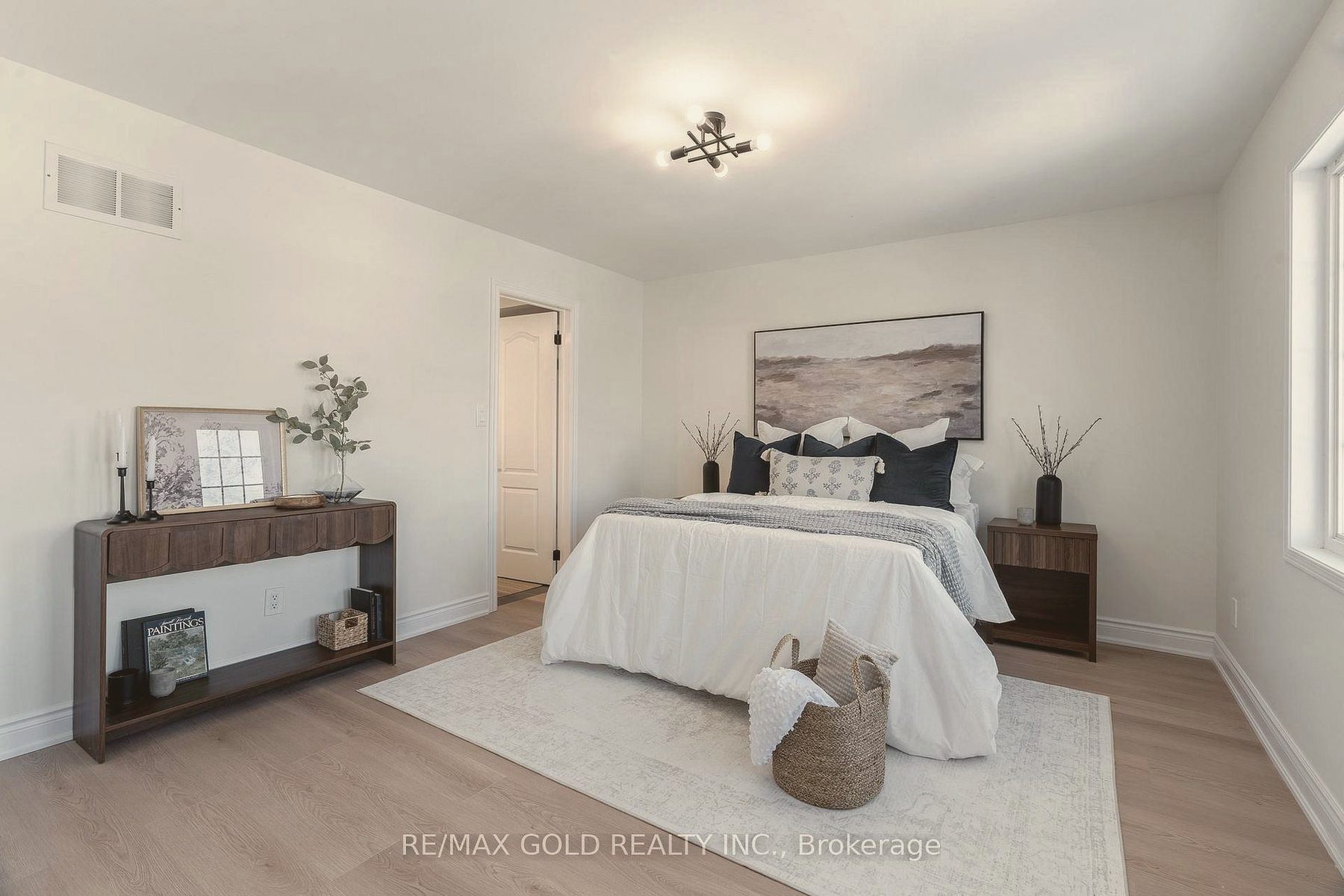 Bedroom with a walnut console, landscape art and a woven basket