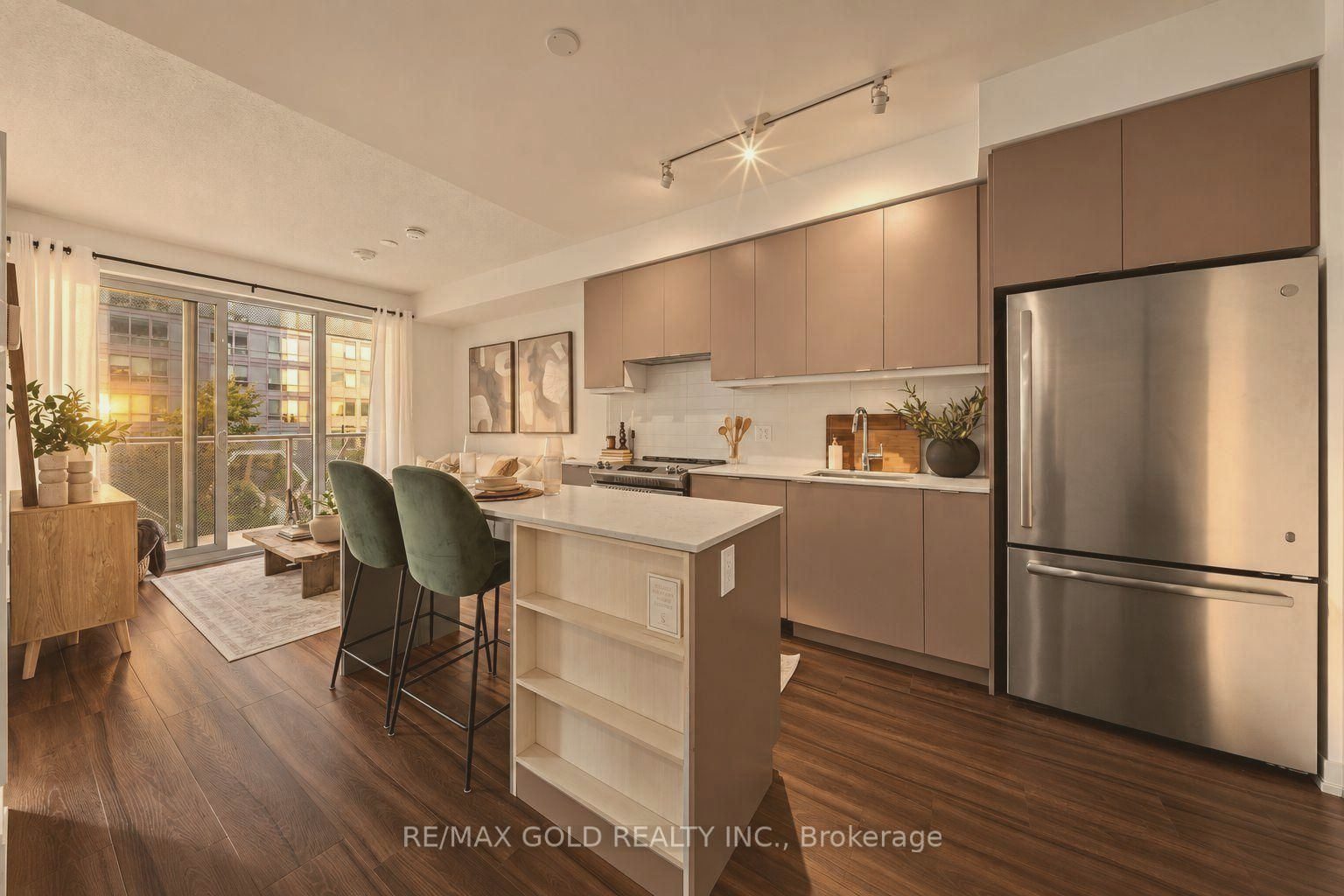 Condo kitchen with blush cabinetry, green velvet stools and a balcony view